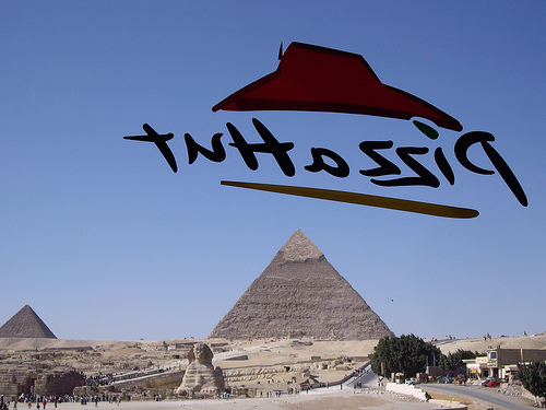 The Pizza Hut logo, in reverse, floats in front of a view of the pyramids at Giza